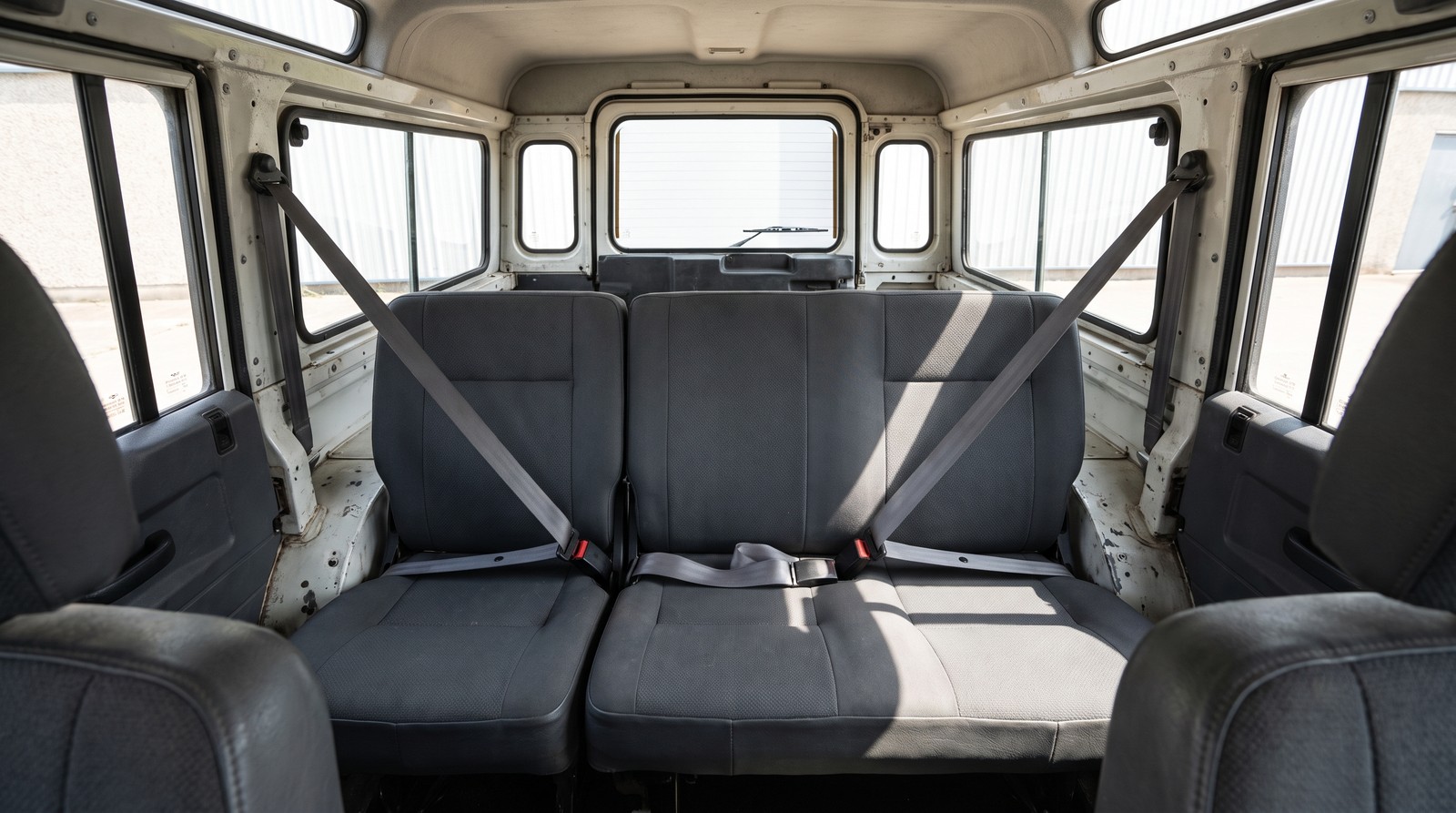 Second row bench of a classic Land Rover Defender 110 station wagon, the outer seats on three point belts and the centre position on a plain lap belt with no anchorage above it