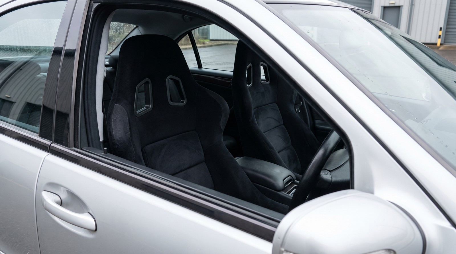 Pair of black Sabelt GT3 FIA bucket seats fitted in a silver Mercedes-Benz C32 AMG W203 saloon, seen through the open driver door window