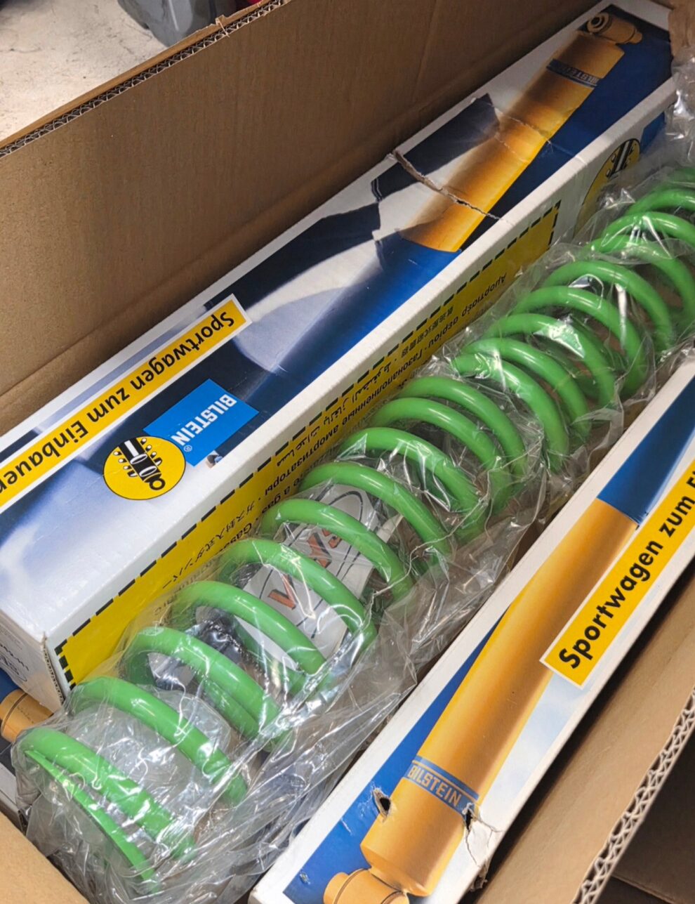 A boxed set of Bilstein dampers and green Eibach springs still in their packaging, waiting to be fitted to the MG ZS