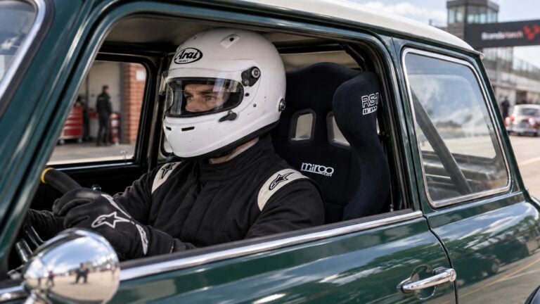 Helmeted Mini Miglia driver checking the fit of a black Mirco RS1 FIA racing seat