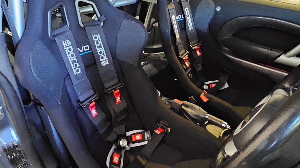 Two black Sparco Evo L bucket seats with black Sparco 4 point harnesses fitted in a customer's Mini Cooper S R53 with a half cage