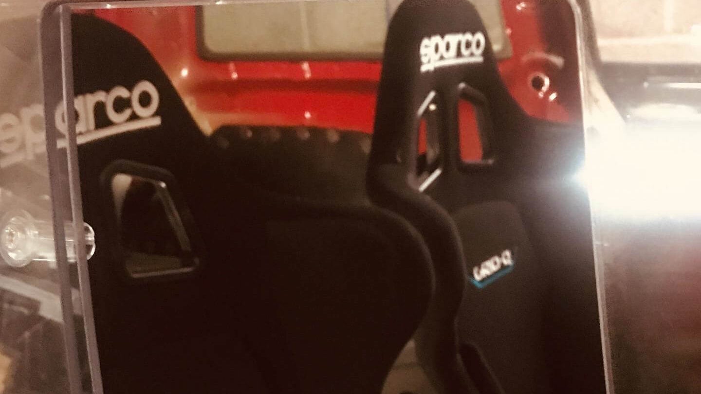 A pair of Sparco Grid Q bucket seats seen through the clear side window of a customer's Mini