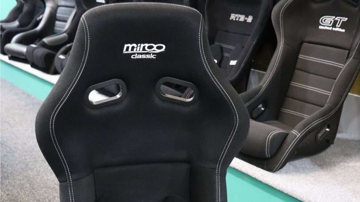A black Mirco Classic FIA bucket seat in front of the Mirco seat display in the GSM Performance showroom