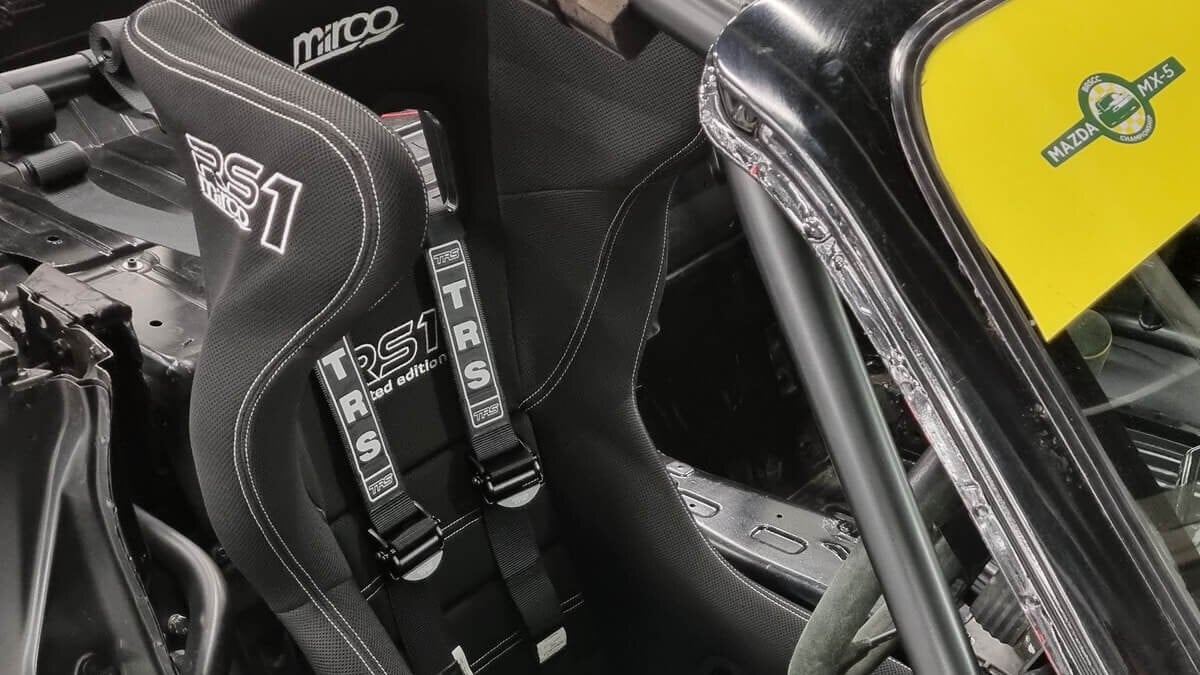 A Mirco RS1 bucket seat with a black TRS harness fitted in a customer's caged Mazda MX-5 race car