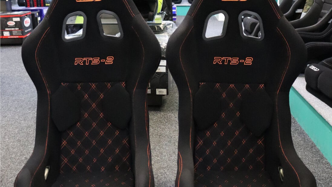 A pair of Mirco RTS-2 seats in black velour with orange diamond stitching on the GSM Performance showroom floor