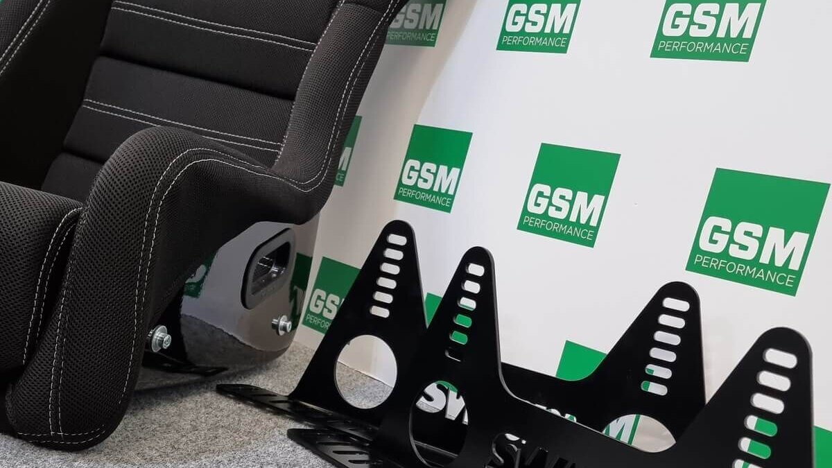 A black Mirco RTS Limited Edition bucket seat beside a pair of black SW Motorsports side mounts in front of a GSM Performance backdrop