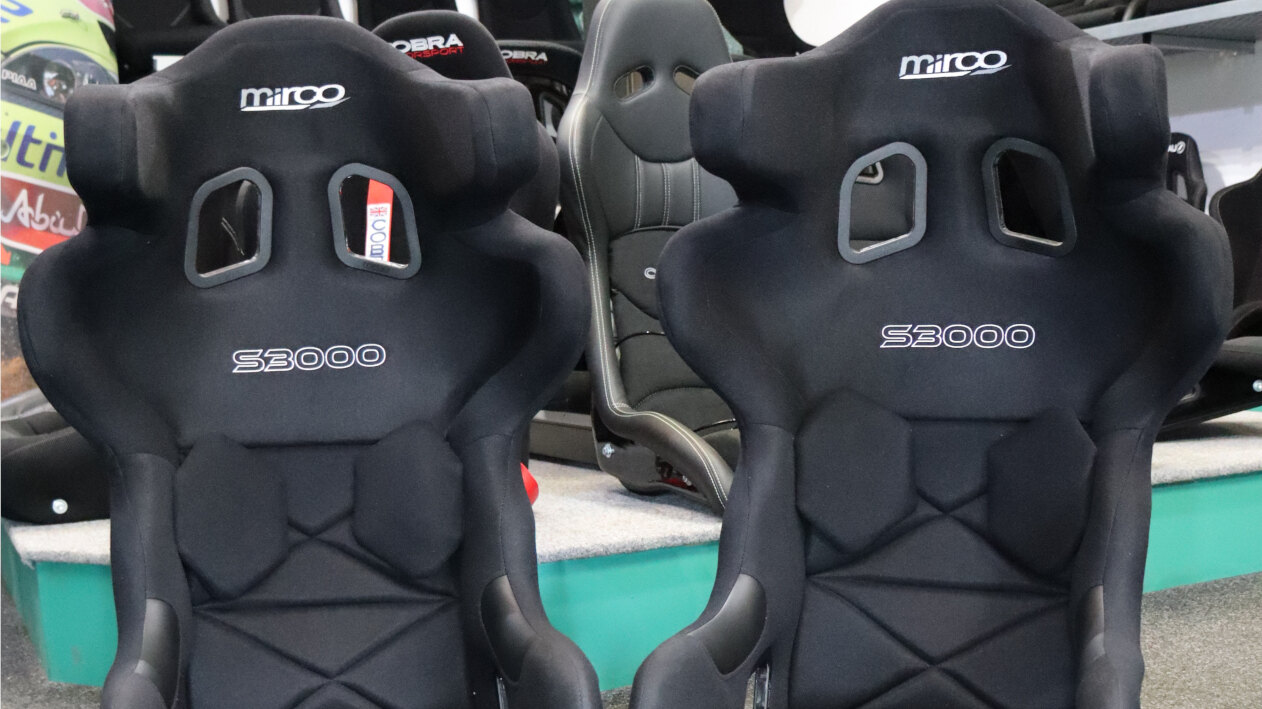 A pair of black velour Mirco S3000 bucket seats on the showroom floor, with Cobra and Recaro seats on the display behind