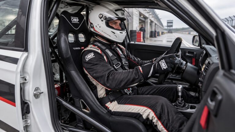 Helmeted driver seated in an OMP TRS-X narrow racing seat fitted inside a compact track car