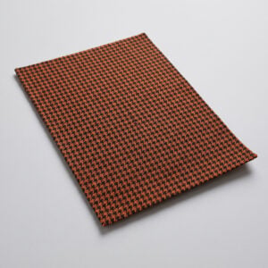 Swatch of orange and black pepita houndstooth upholstery cloth showing the fine woven check