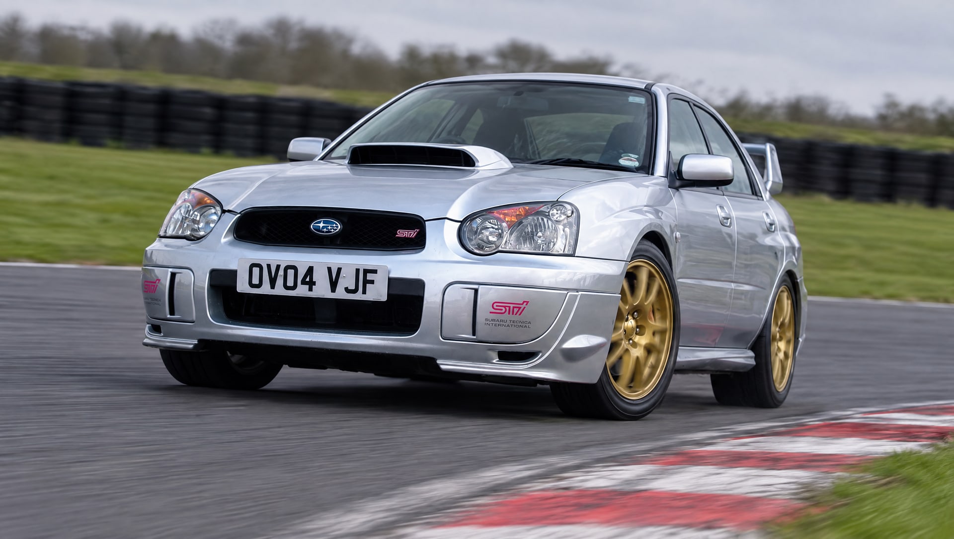 Silver 2004 Subaru Impreza WRX STI, registration OV04 VJF, cornering on a UK race circuit on a track day