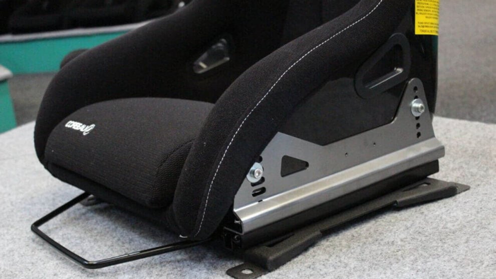A black Corbeau bucket seat on a PCI Racing sliding frame with side mounts, on the showroom carpet
