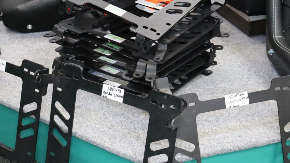 A stack of black Planted Technology seat frames on the showroom plinth, with labelled frames leaning against it