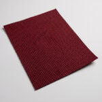 Swatch of red and black houndstooth upholstery cloth showing the fine woven check