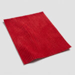Swatch of red fine wale corduroy upholstery fabric showing the narrow parallel ribs and soft nap