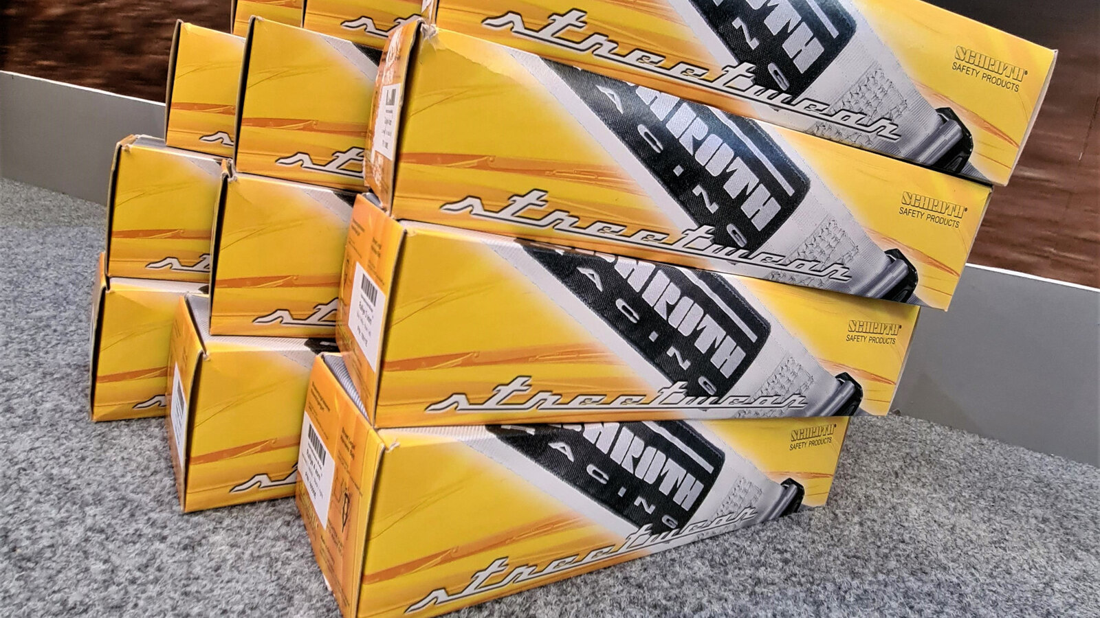 Boxed Schroth Racing street harnesses stacked on the carpet of the GSM Performance showroom