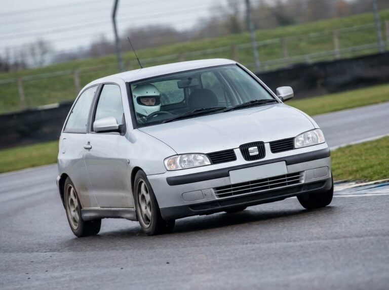 Seat Cordoba Mk2 cornering on a British race circuit, helmeted driver visible through the windscreen