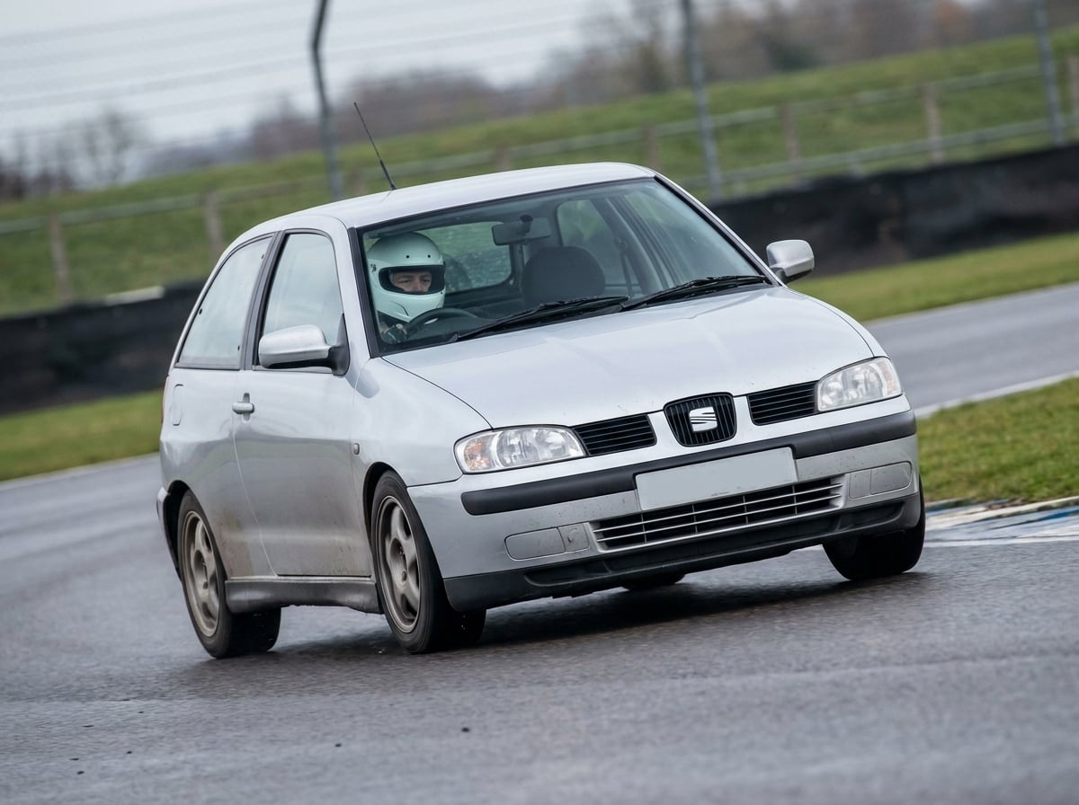 Seat Cordoba Mk2 cornering on a British race circuit, helmeted driver visible through the windscreen