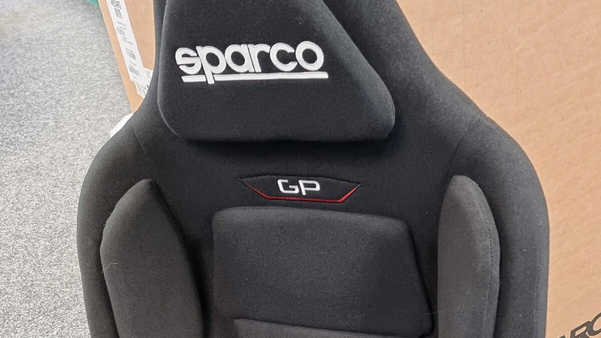 The upper back and headrest of a black Sparco GP gaming seat standing in the GSM Performance showroom