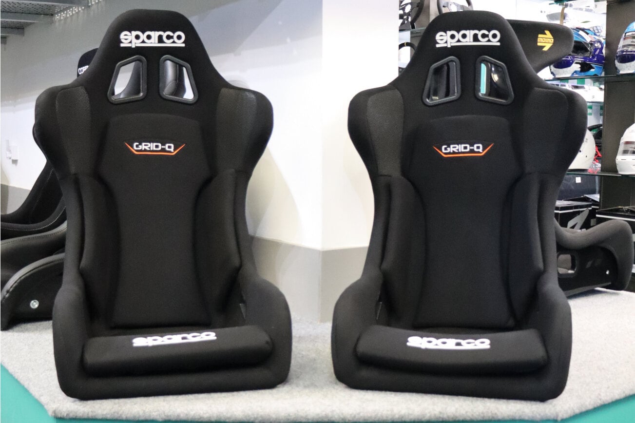 Two black Sparco Grid Q track day bucket seats with orange Grid Q logos on the GSM Performance showroom plinth