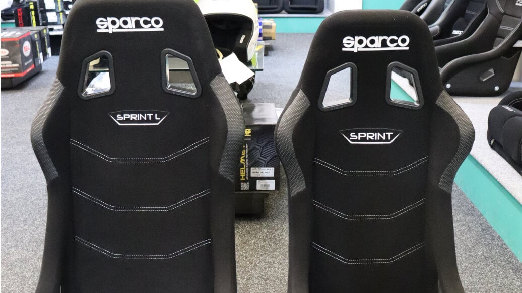 A Sparco Sprint L and a standard Sparco Sprint 2025 bucket seat side by side on the showroom floor