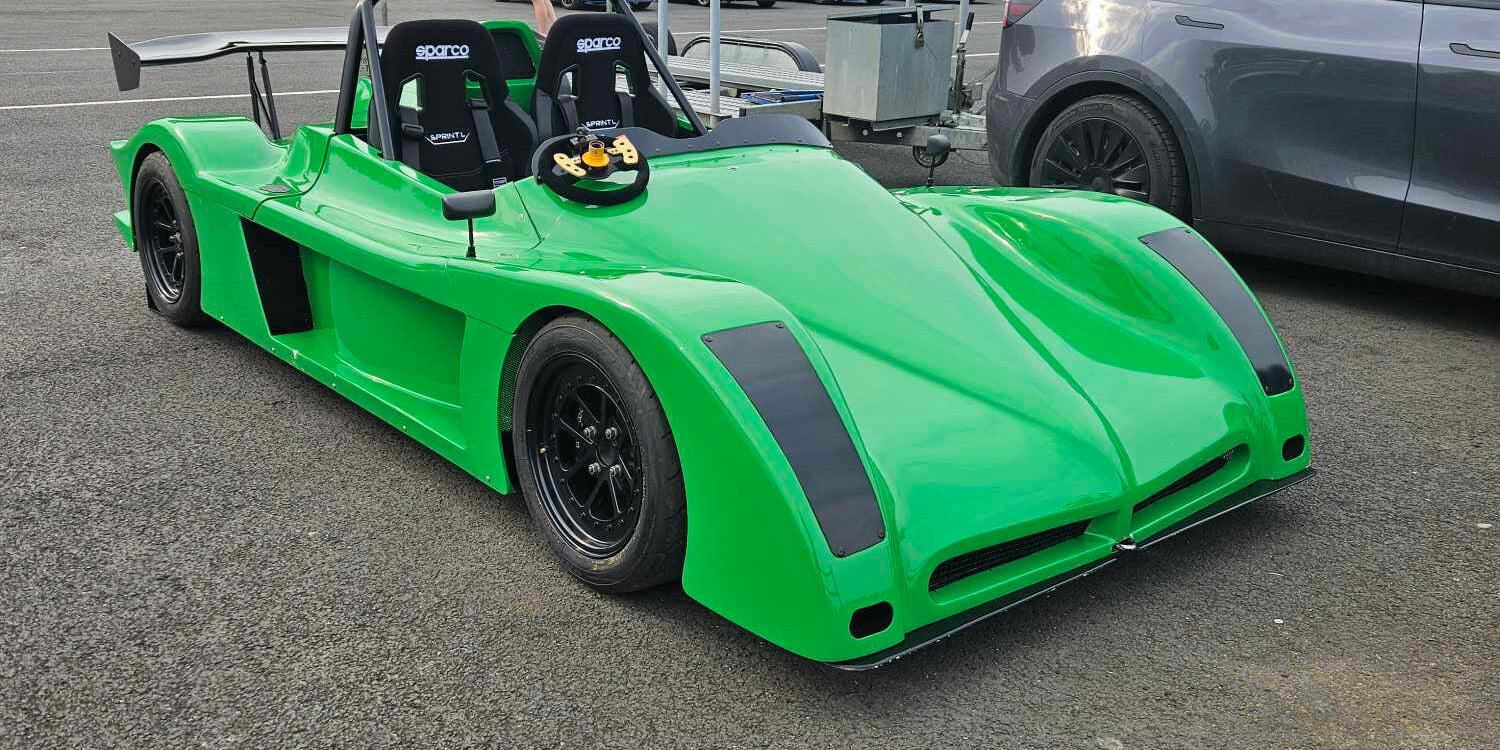 Green Spire GTR kit car with two black Sparco Sprint L bucket seats, parked in a circuit paddock