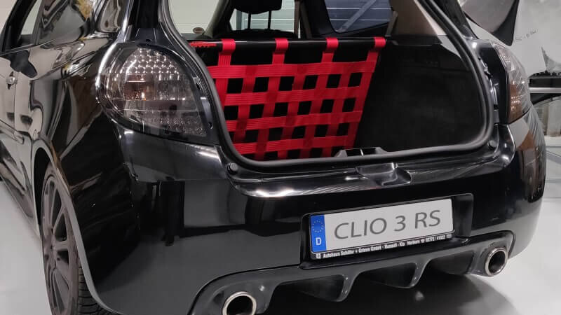 A black Renault Clio 3 RS with its tailgate open, showing a Stern Performance strut bar and red net behind the front seats