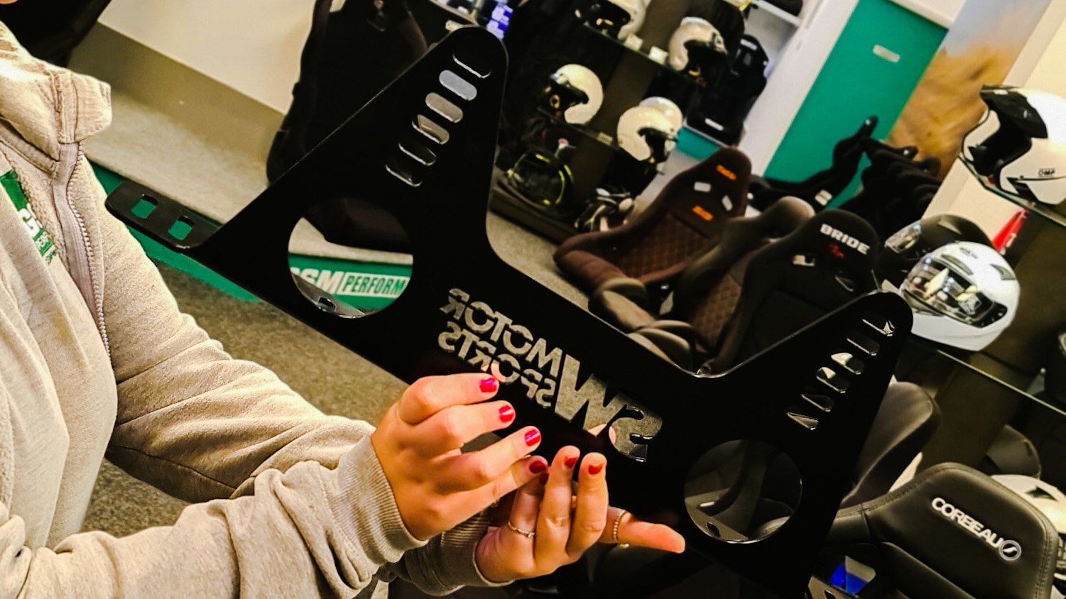 A member of the team holding up a black SW Motorsports bucket seat side mount in the showroom