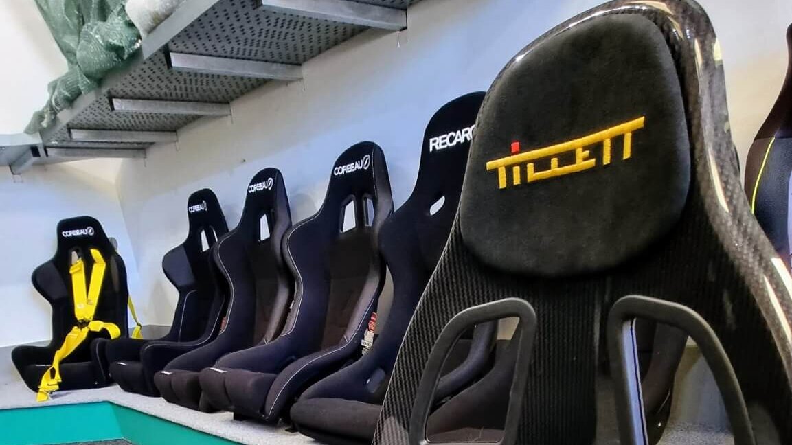 A carbon Tillett B6 XL Screamer seat still in its protective bag in front of a row of bucket seats in the SportSeats4u showroom
