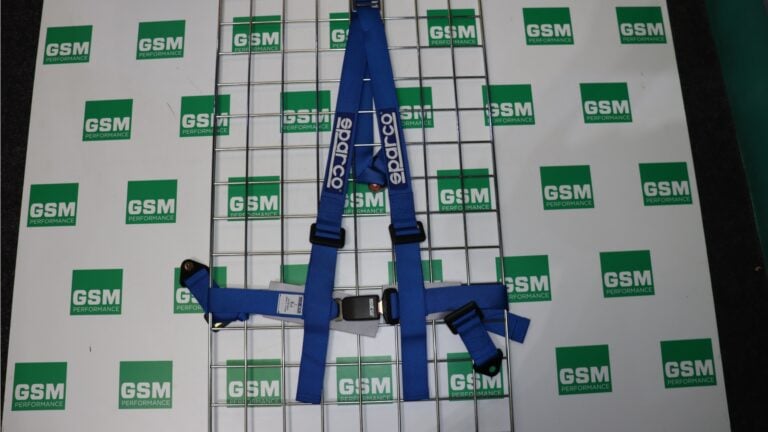 A Sparco Club H-3 three point road harness in blue on the GSM Performance display board, showing one tail strap splitting into two shoulder straps down to a push button buckle, with the lap belt running out to each side and nothing below the buckle