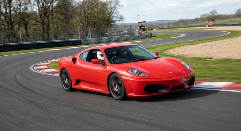 Ferrari F430 Berlinetta cornering on a British race circuit, helmeted driver visible