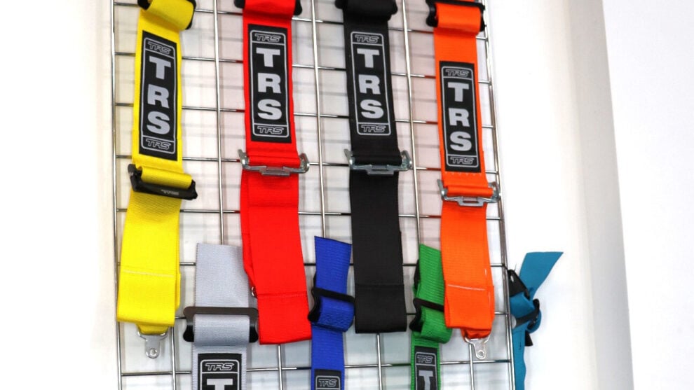 TRS harness straps in yellow, red, black, orange, grey, blue, green and turquoise hanging on a wire display in the GSM Performance showroom