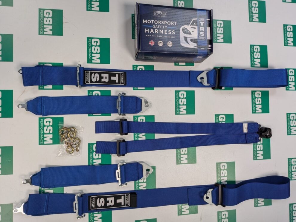 A blue TRS Magnum 6 point harness laid out in its separate straps beside its box