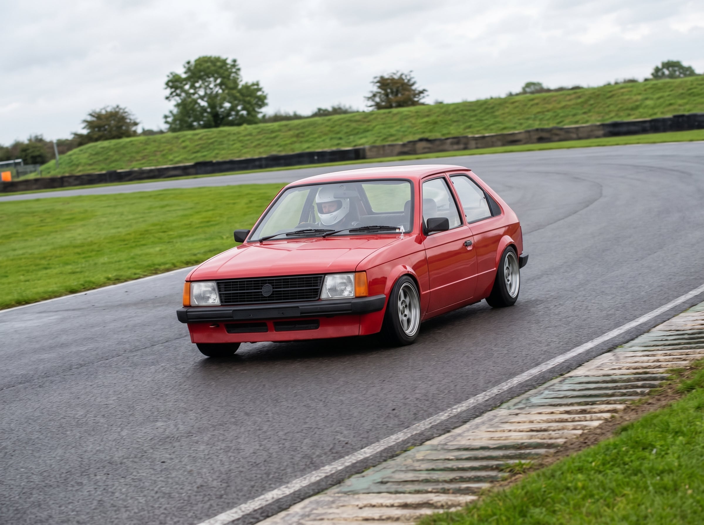 Red Vauxhall Astra Mk1 Kadett cornering on a British race circuit