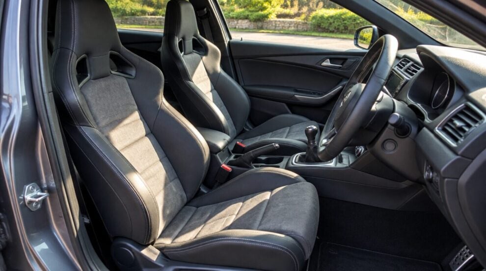 Black reclining sport seats with grey fabric centres fitted in the front of a hatchback, seen through the open door