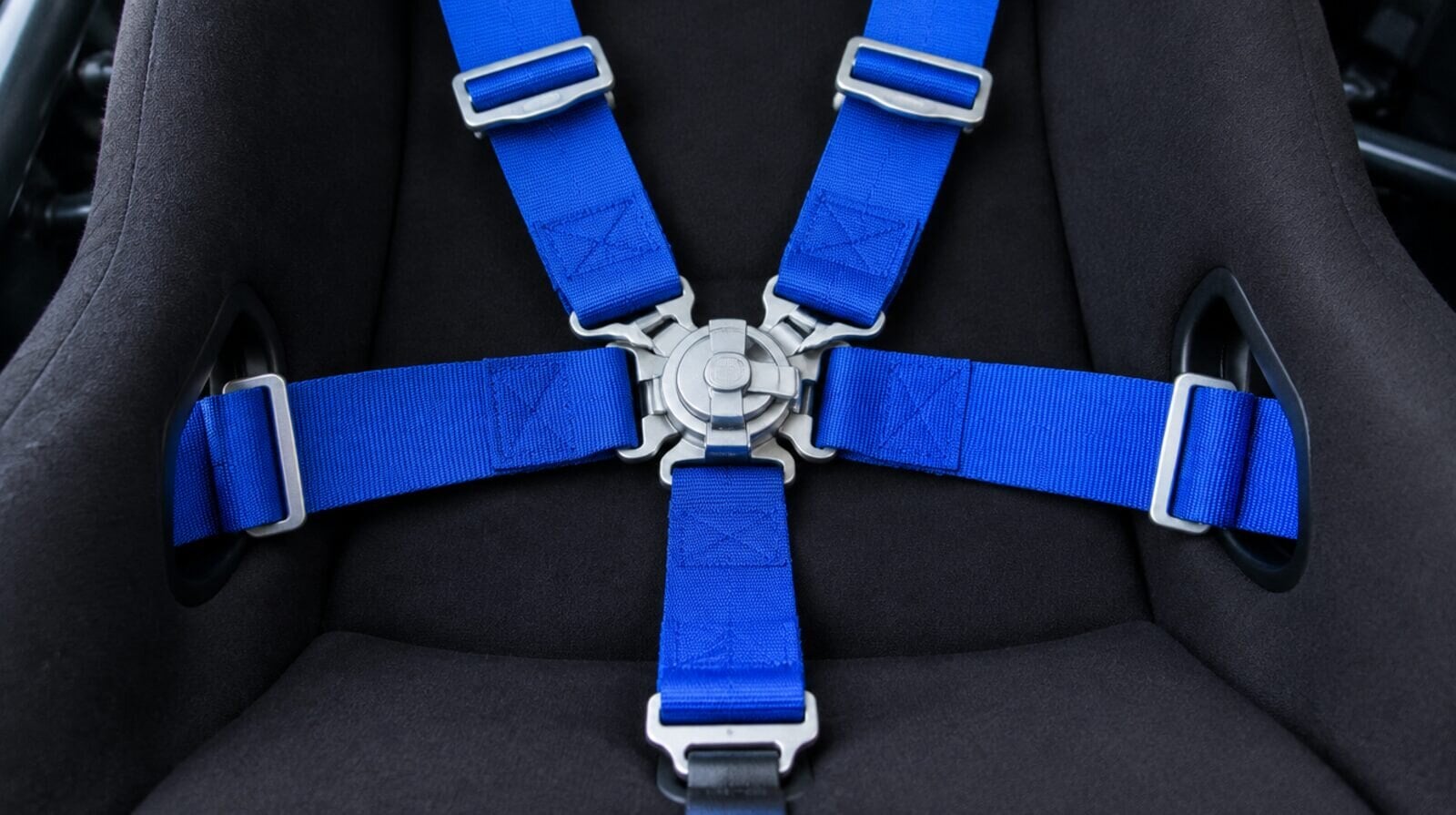 Racing harness buckle across a bucket seat