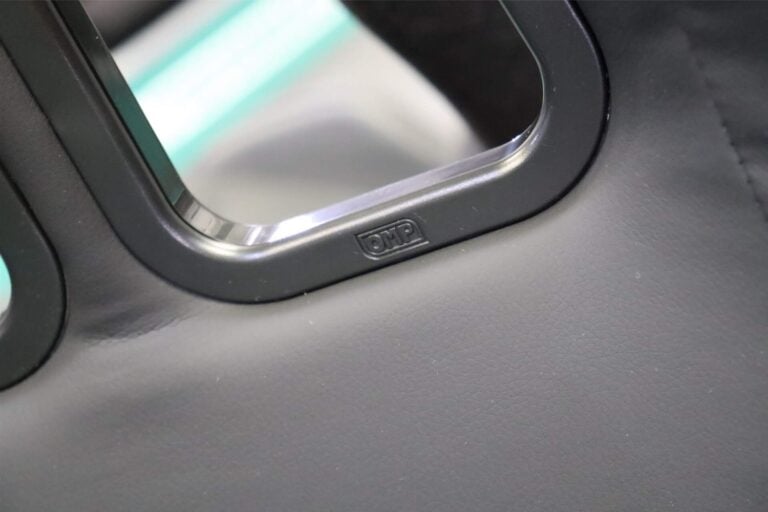 The fabric tucked neatly under a black plastic harness slot surround on an OMP seat