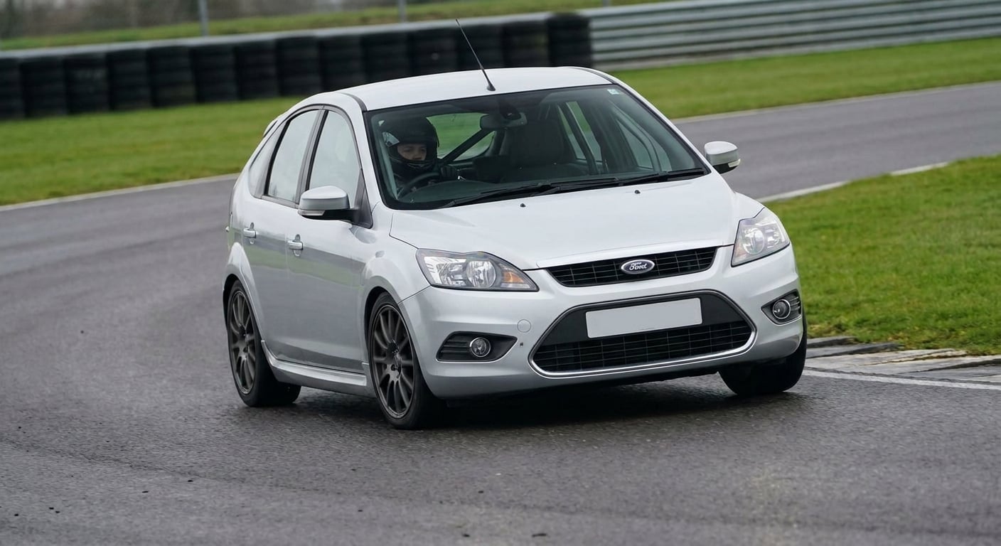 Silver Ford Focus Mk2 hatchback cornering on a British race circuit with helmeted driver visible