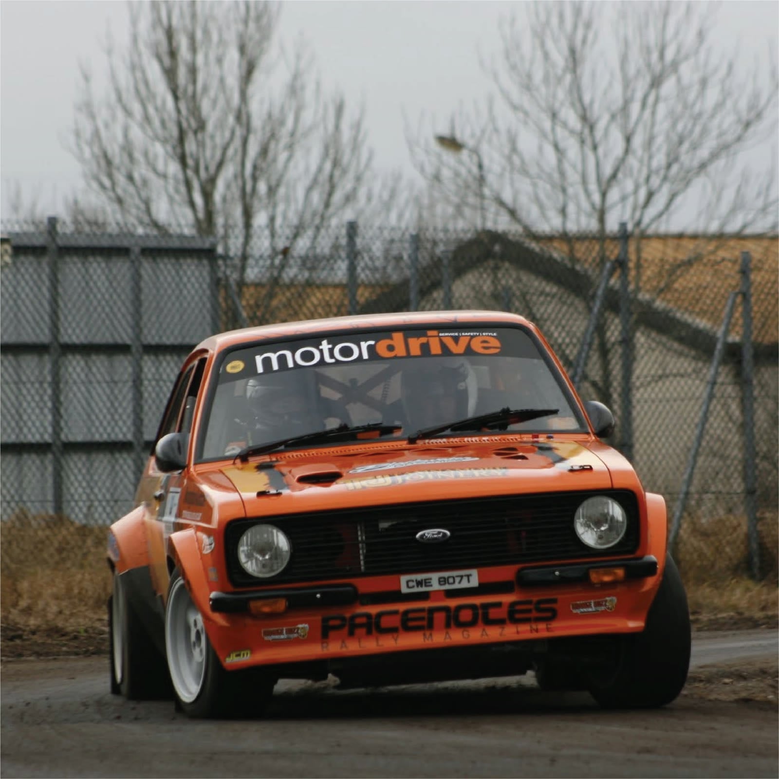 Orange rally car with Motordrive branding in action
