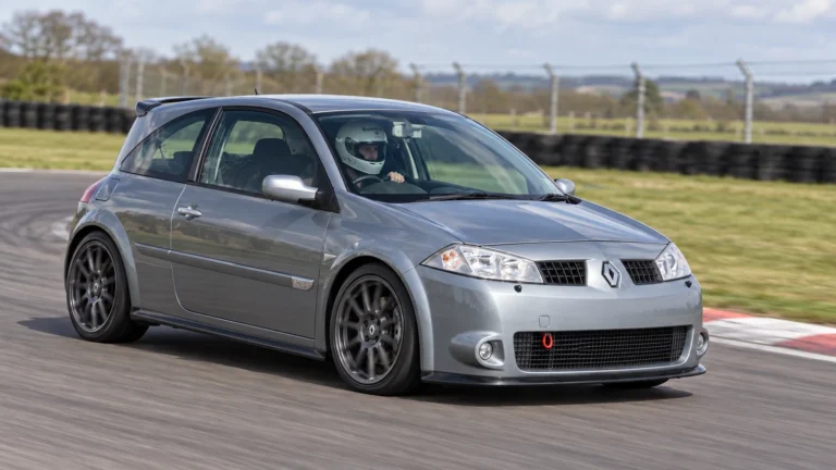 Modified grey Renault Megane 225 Mk2 with a roof spoiler and aftermarket wheels, driven on a dry circuit by a helmeted driver