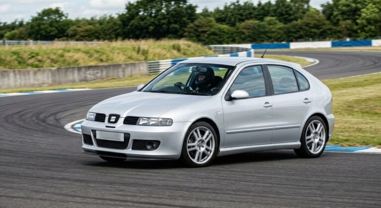 Seat Leon Mk1 Cupra cornering on a British race circuit, helmeted driver at the wheel